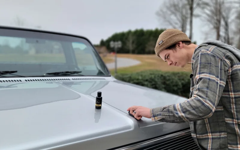 Applying coating to a silver pickup truck in a driveway