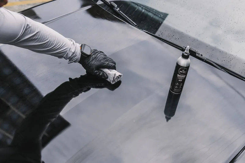 Diamond AI being applied by hand to a dark painted bonnet